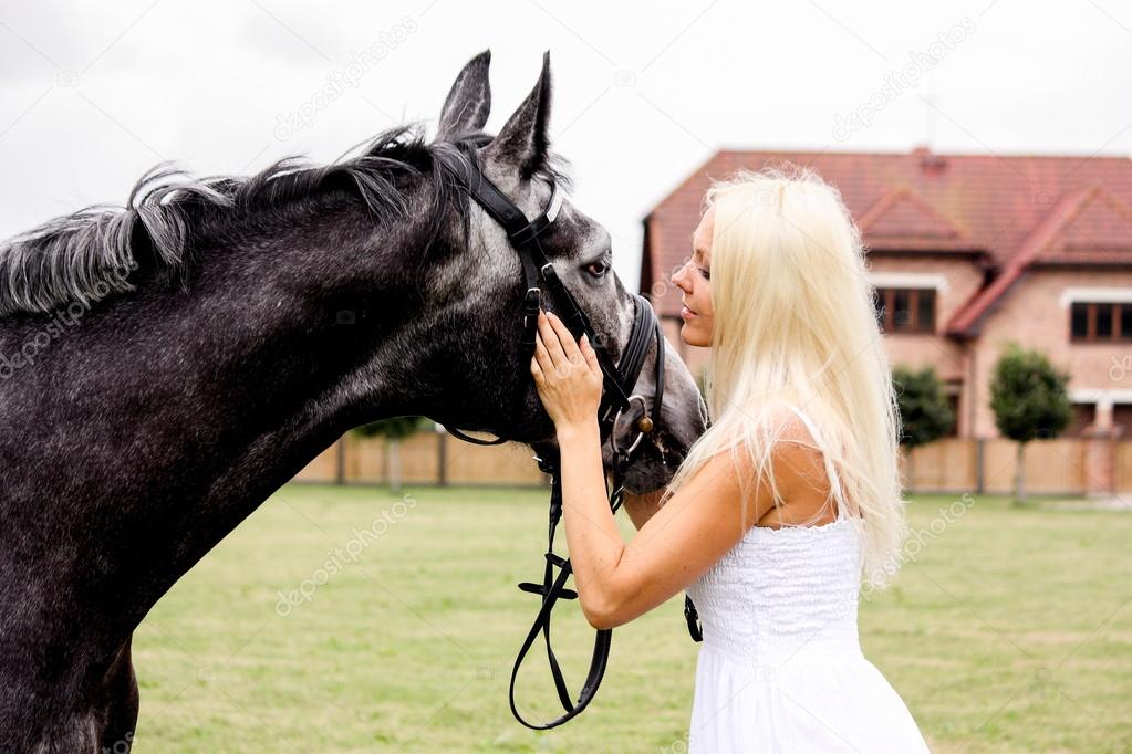 Portrait of beautiful blonde woman and gray horse at the wedding
