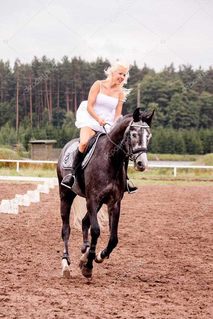 Beautiful bride riding gray horse in summer