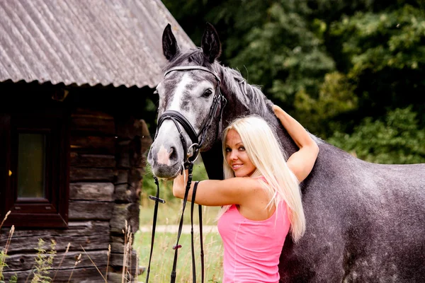 Beautiful blonde woman and her horse in rural area — Stock Photo, Image