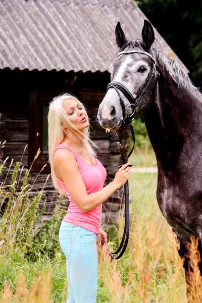 Krásná blondýnka a její koně ve venkovské oblasti — Stock fotografie