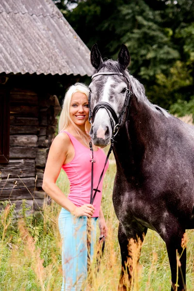 Beautiful blonde woman and her horse in rural area — Stock Photo, Image