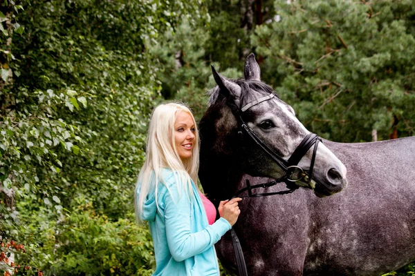 Beautiful blonde woman and her horse in rural area — Stock Photo, Image