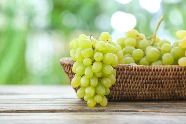 Açık havada masada olgun üzümlü hasır kase.