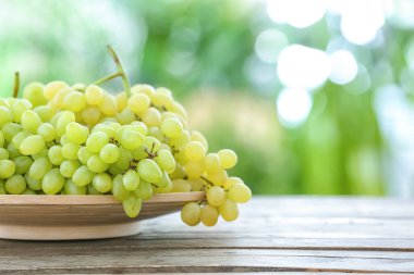 Açık havada masada olgun üzümlerle dolu bir tabak.