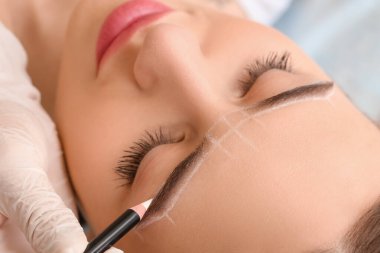 Güzellik salonunda kaş düzeltme prosedürüne tabi tutulan genç bir kadın.