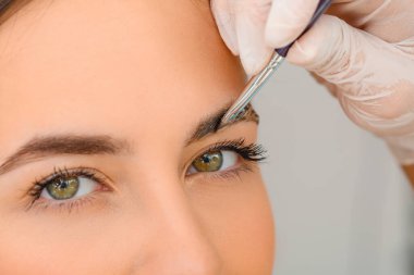 Güzellik salonunda kaş düzeltme prosedürüne tabi tutulan genç bir kadın.