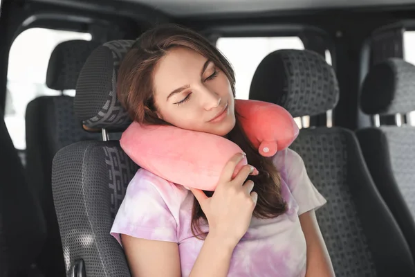 一位漂亮的年轻女子坐在车上 带着旅行枕头 — 图库照片
