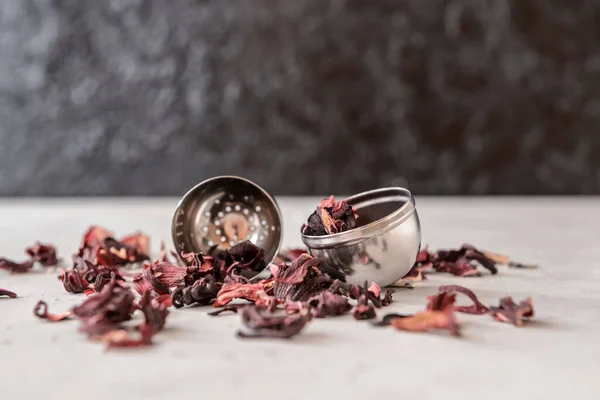 Strainer with dry hibiscus tea on table