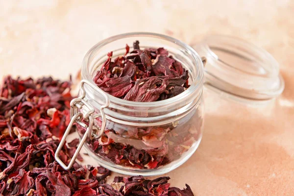 Jar with dry hibiscus tea on table