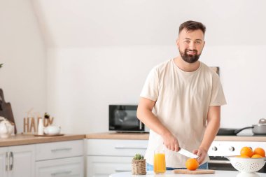 Adam mutfakta turuncu kesiyor.