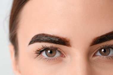 Kaşlarını boyayan genç bir kadın, yakın plan.