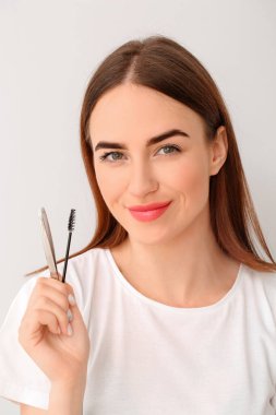 Açık arkaplanda kaş düzeltme prosedürü için aletleri olan genç bir kadın.