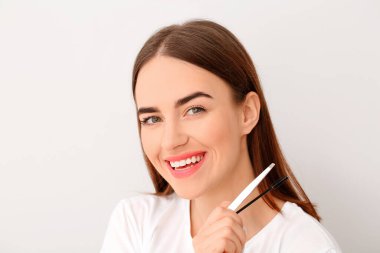 Açık arkaplanda kaş düzeltme prosedürü için aletleri olan genç bir kadın.