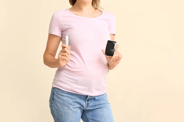 Schwangere Diabetikerin Mit Digitalem Glukometer Und Lanzettstift Auf Farbigem Hintergrund — Stockfoto