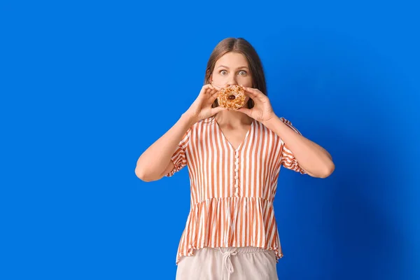 面白いです若いです女性とともに甘いですドーナツ上の色の背景 — ストック写真