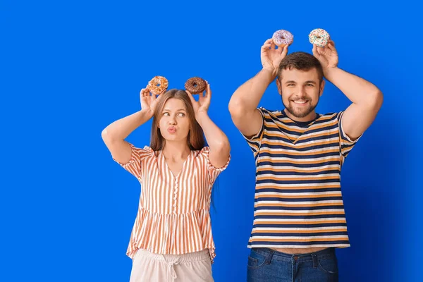 Pareja Joven Con Rosquillas Dulces Sobre Fondo Color — Foto de Stock