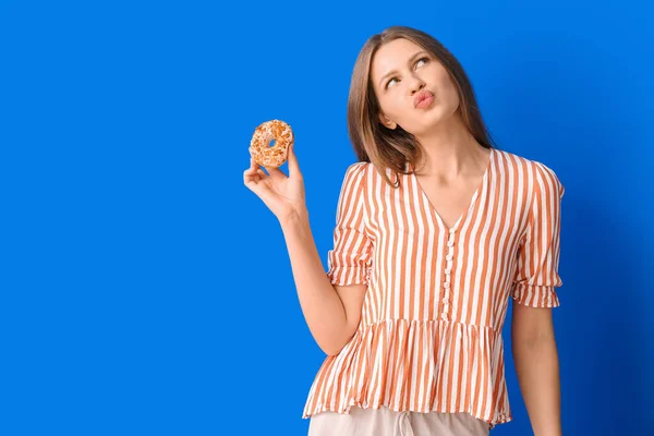 Mujer Joven Reflexiva Con Rosquilla Dulce Sobre Fondo Color —  Fotos de Stock