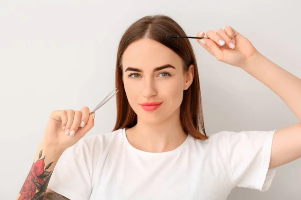 Junge Frau Mit Werkzeugen Für Augenbrauenkorrektur Auf Hellem Hintergrund — Stockfoto