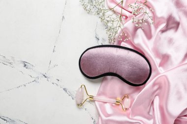 Açık arkaplanda pijama, uyku maskesi ve masaj aracı