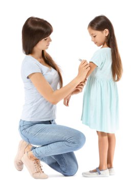 Anne beyaz arka planda diyabetik kızına insülin enjekte ediyor.