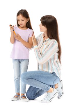 Anne ve şeker hastası kız beyaz arka planda kan örneği alıyorlar.