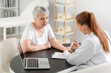 Senior diabetic woman visiting doctor in clinic clipart