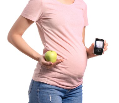 Beyaz arka planda dijital glukometresi ve elması olan hamile diyabetik kadın.