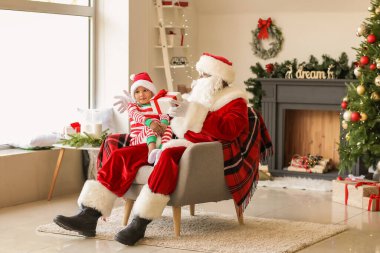 Afro-Amerikan Noel Baba ve Noel arifesinde evde hediyeli şirin bir çocuk.