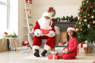 Afro-Amerikan Noel Baba ve Noel arifesinde evde hediyeleri olan tatlı bir kız.