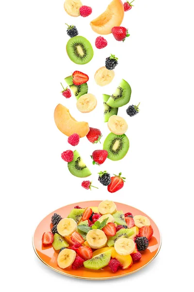 Plate with delicious fruit salad and flying ingredients on white background