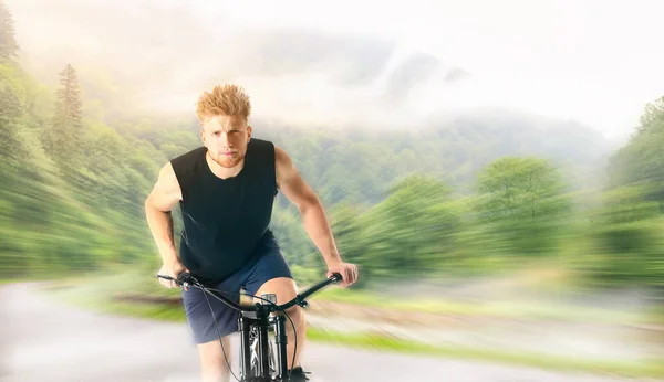 Young man riding bicycle in countryside