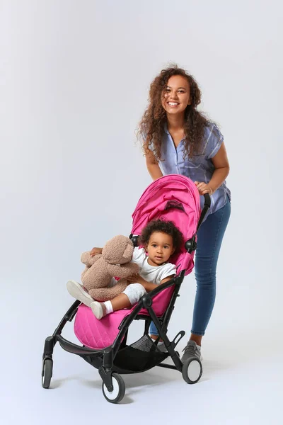 アフリカ系アメリカ人女性と彼女のかわいいです赤ちゃんでベビーカー上の光の背景 — ストック写真