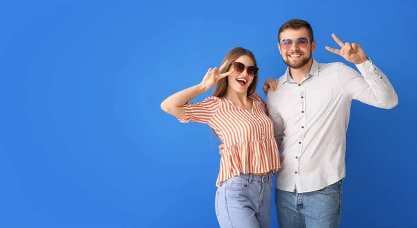 Young Couple Stylish Sunglasses Showing Victory Gesture Color Background — Stock Photo, Image