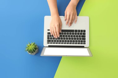 Renkli arka planda modern dizüstü bilgisayarı olan kadın elleri