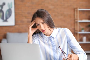 Evde dizüstü bilgisayarı olan stresli genç bir kadın.