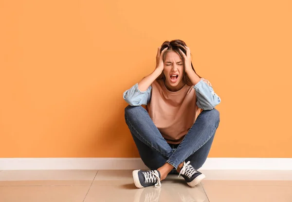 Stressed young woman near color wall