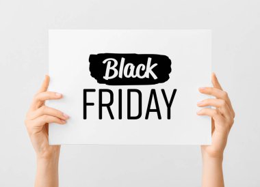 Açık arkaplanda Kara Cuma yazılı kart tutan kadın elleri