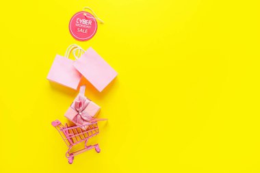 Çantalı alışveriş arabası, hediye kutusu ve etiketli CYBER Pazartesi günü renkli arka planda satış