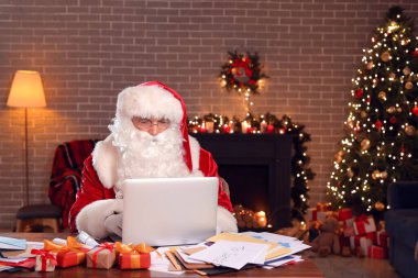 Bilgisayarlı Noel Baba Noel arifesinde evde e-postaları kontrol ediyor.