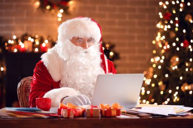 Bilgisayarlı Noel Baba Noel arifesinde evde e-postaları kontrol ediyor.