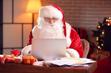Bilgisayarlı Noel Baba Noel arifesinde evde e-postaları kontrol ediyor.