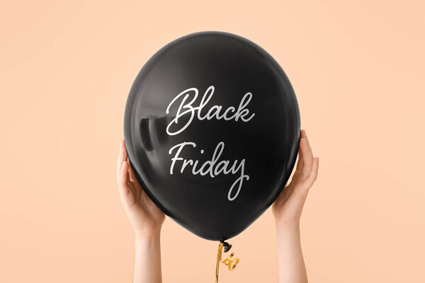 Руки женщины держат воздушный шар с текстом "Черная пятница" на цветном фоне