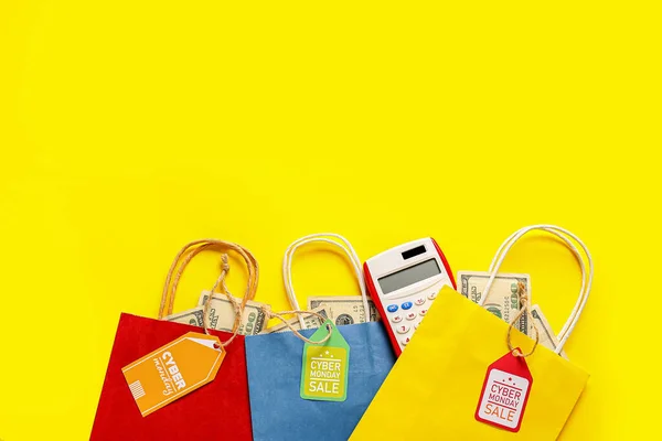 Shopping bags with money, calculator and tags with text CYBER MONDAY SALE on color background