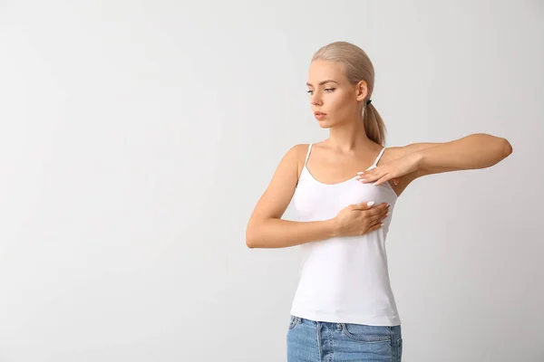 灰色の背景で胸をチェックする若い女性 癌意識の概念 — ストック写真