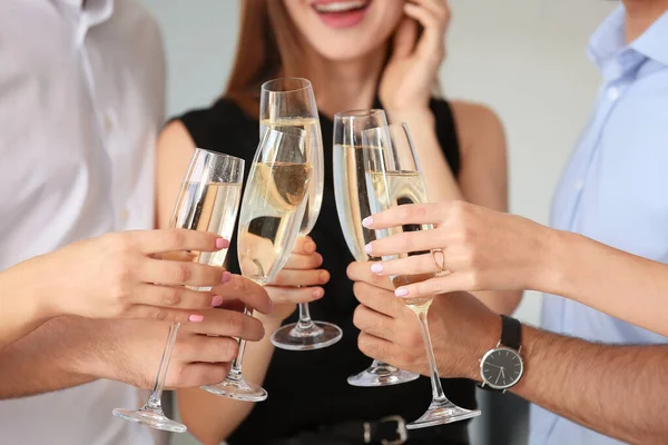 Young people drinking tasty champagne at party in office