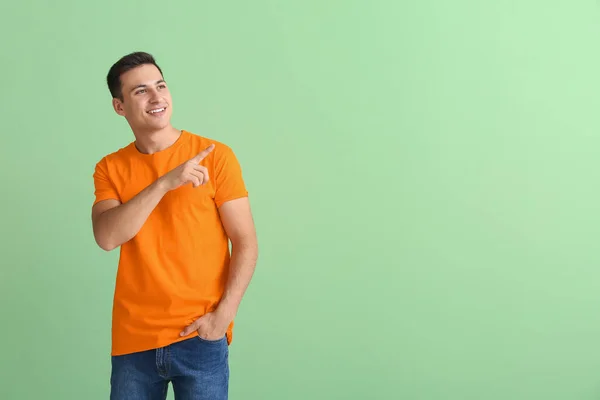 Knappe Jongeman Oranje Shirt Wijzend Naar Iets Kleur Achtergrond — Stockfoto