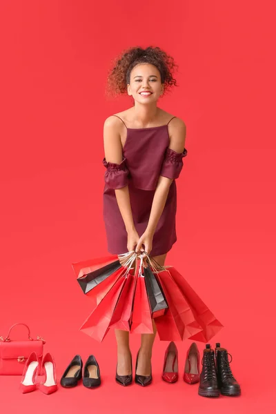 色の背景にショッピングバッグや靴を持つ美しいアフリカ系アメリカ人女性 ブラック フライデー販売 — ストック写真