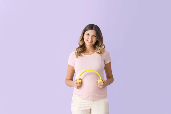 美しいです妊娠中の女性置くヘッドフォン彼女の腹に色の背景 — ストック写真