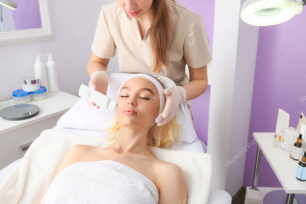 Woman undergoing procedure of facial peeling in beauty salon