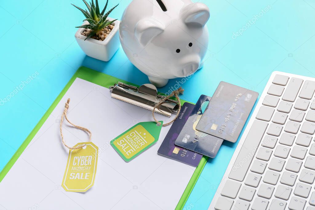 Computer keyboard, piggy bank, credit cards and tags with text CYBER MONDAY SALE on color background